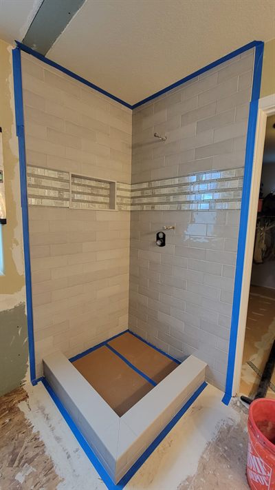 Custom shower part-way through tiling with protective tape on the edges