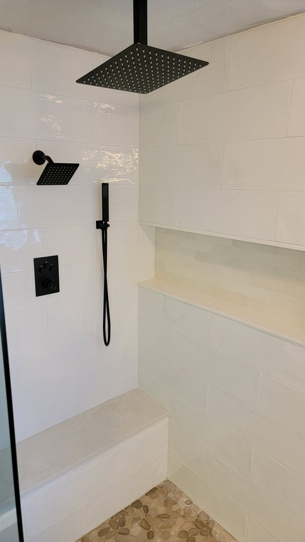 Custom tiled shower in white tile with black rainfall fixtures and a built-in bench, built by Master's Flooring & Custom Tile