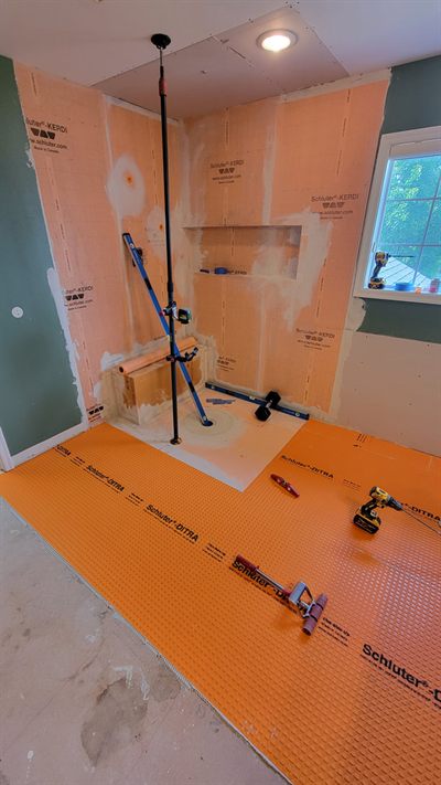 Orange bonded waterproofing membrane installed over shower walls before tiling