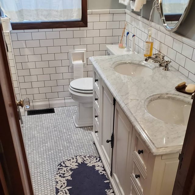 Finished bathroom with marble double vanity and subway tile walls