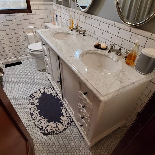 Finished bathroom with double vanity, round mirrors, and subway tile walls