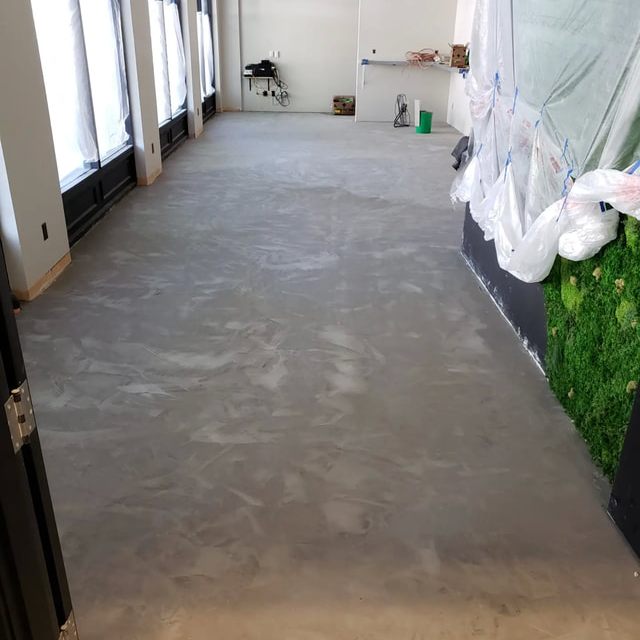 Smooth troweled concrete floor finish in a commercial space with a moss accent wall in the background.