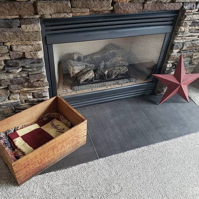 Stacked stone fireplace with dark gray tile hearth