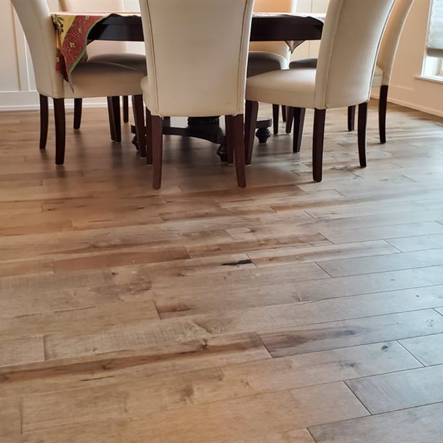 Dining room with a dark wood table and cream chairs on a wide-plank wood floor.
