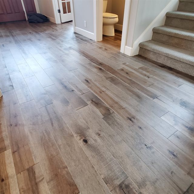 Entryway with wood floor transitioning to carpeted stairs, with a bathroom visible through a doorway.
