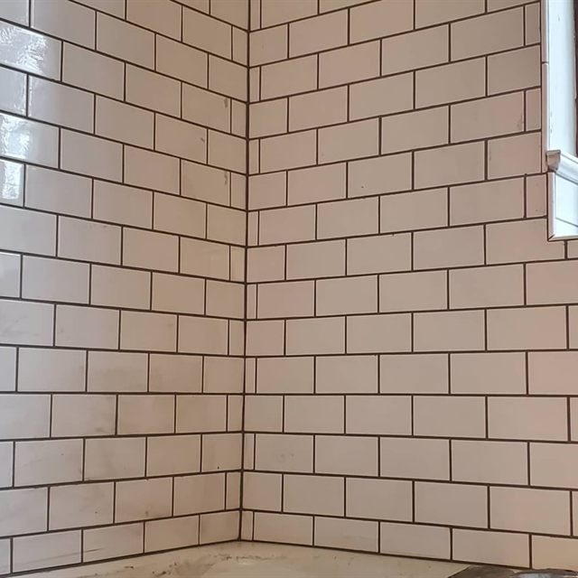 Close-up of white subway tile corner with dark grout lines