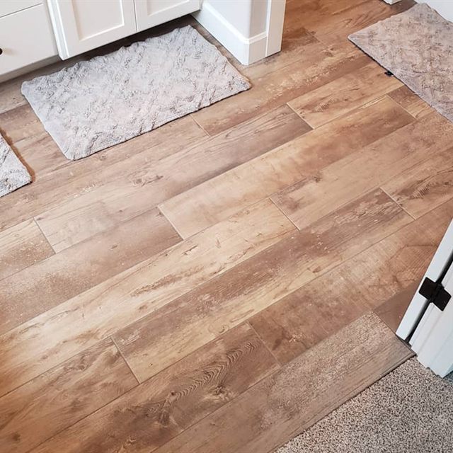 Wood-look plank tile floor with bath mats near a bathroom vanity